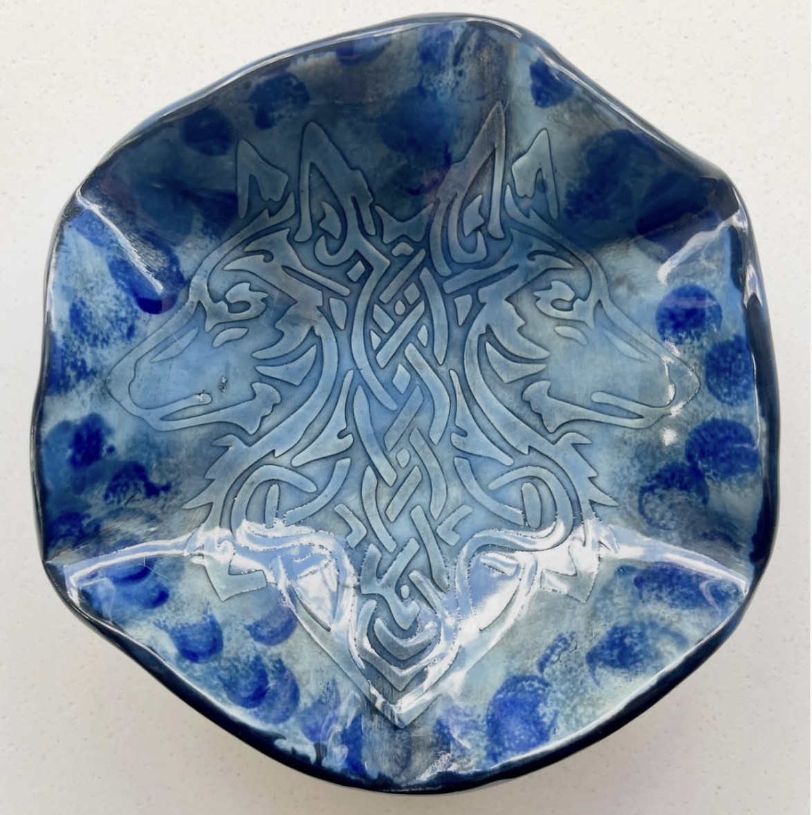 Handbuilt ceramic bowl with carved Celtic wolf design in blue glaze